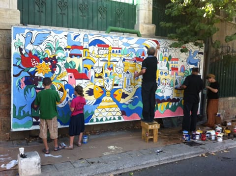 מיכאל אלקיים מצייר על לוח קיר ברחוב הע"ח בשכונת מוסררה בירושלים